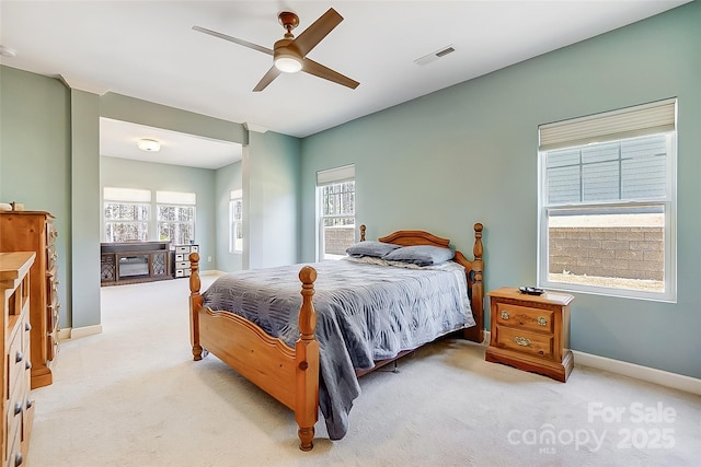 bedroom with light colored carpet, visible vents, and multiple windows