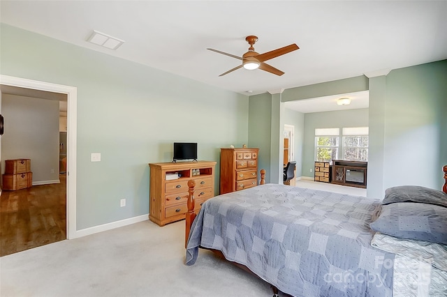 bedroom with light carpet, visible vents, baseboards, and a ceiling fan