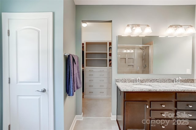 full bath featuring double vanity, a stall shower, a sink, and baseboards