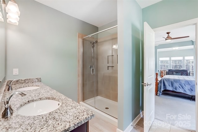 ensuite bathroom with connected bathroom, a stall shower, a sink, and a ceiling fan