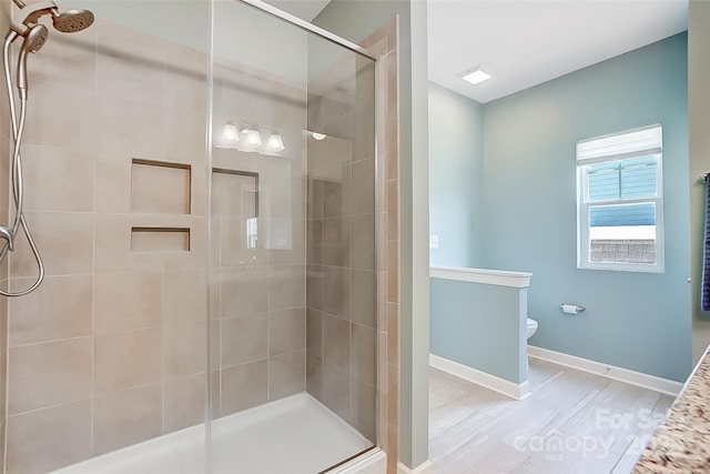 bathroom with toilet, a shower stall, and baseboards