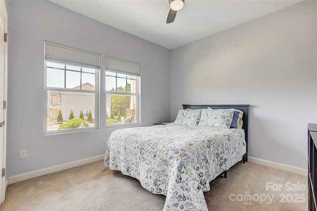 bedroom with a ceiling fan, light carpet, and baseboards