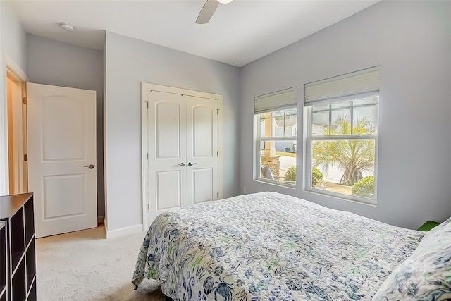 bedroom featuring a ceiling fan, a closet, light colored carpet, and baseboards