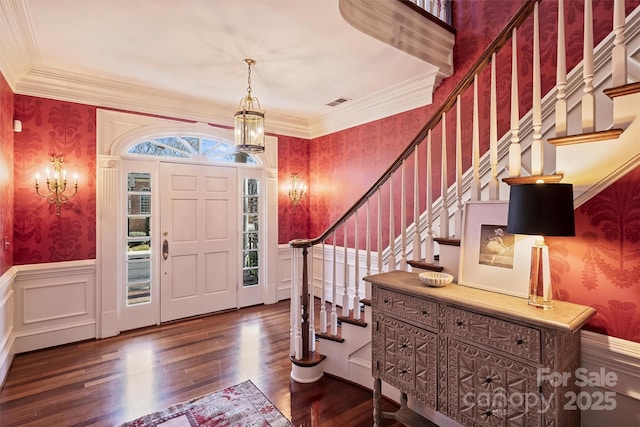 foyer with ornamental molding, wainscoting, and wallpapered walls