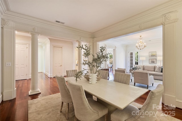 dining area with dark wood-style flooring, decorative columns, a notable chandelier, visible vents, and ornamental molding