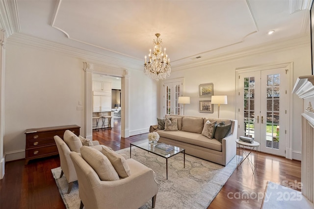 living room with crown molding, visible vents, an inviting chandelier, wood finished floors, and baseboards