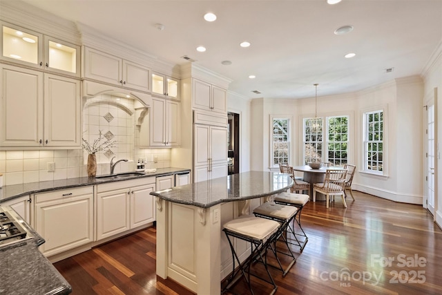 kitchen featuring dark wood-style flooring, ornamental molding, backsplash, and a sink