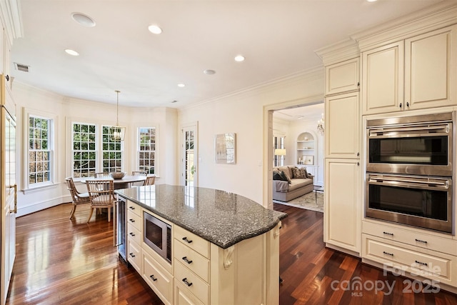 kitchen with visible vents, stainless steel appliances, cream cabinetry, and dark stone counters