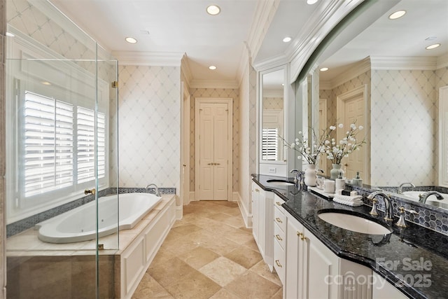 bathroom featuring a garden tub, ornamental molding, a sink, and wallpapered walls