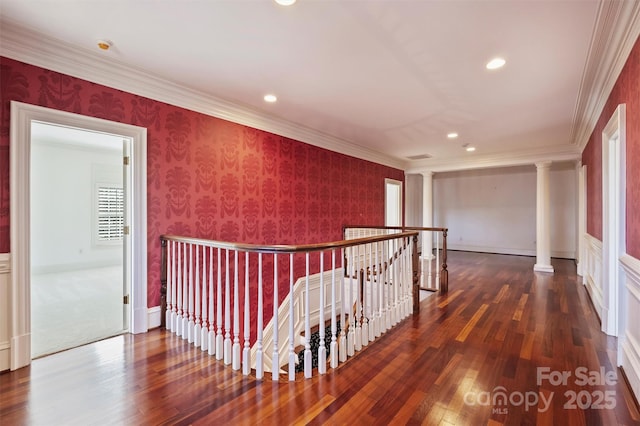 corridor with ornate columns, crown molding, wallpapered walls, and an upstairs landing