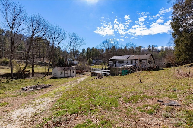 view of yard with a storage shed, fence, a deck, and an outdoor structure