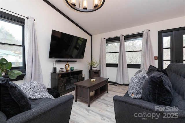 living room featuring light wood finished floors, plenty of natural light, visible vents, and vaulted ceiling