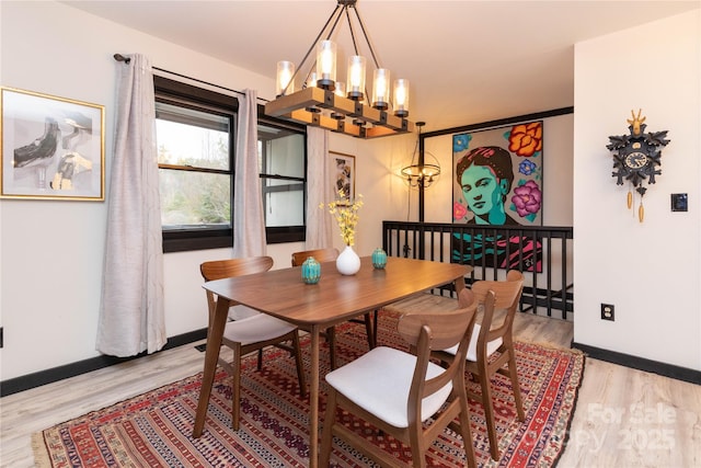 dining area with light wood-type flooring, baseboards, and a chandelier