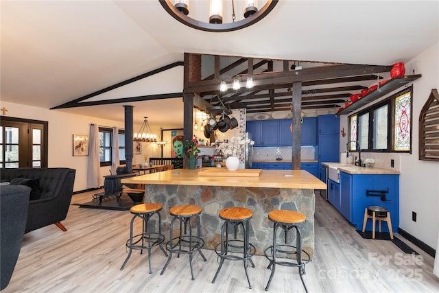 kitchen featuring lofted ceiling, blue cabinetry, a breakfast bar area, and wooden counters