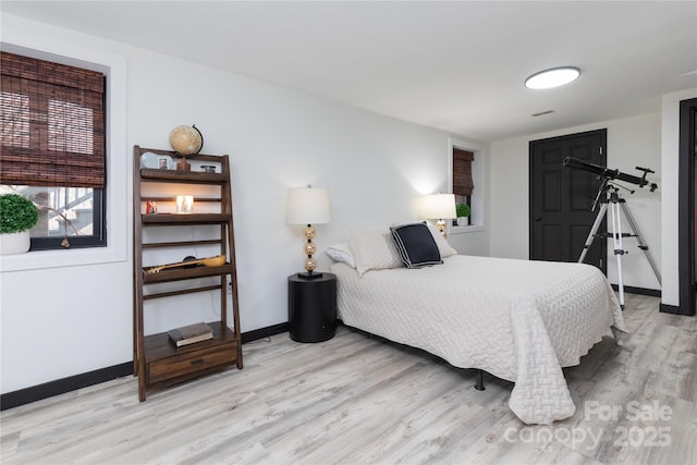 bedroom featuring light wood-type flooring, visible vents, and baseboards