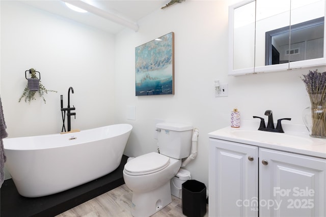 full bath featuring a freestanding bath, vanity, toilet, and wood finished floors