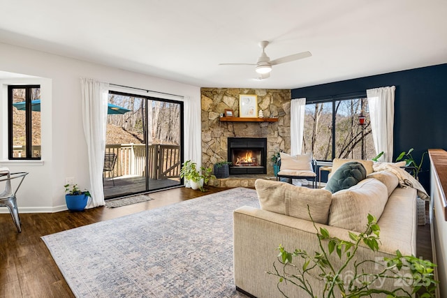 living room with baseboards, ceiling fan, dark wood-style floors, and a fireplace