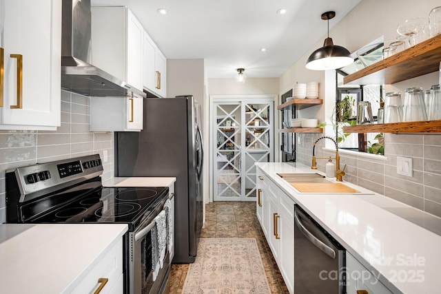 kitchen featuring open shelves, wall chimney exhaust hood, tasteful backsplash, a sink, and appliances with stainless steel finishes