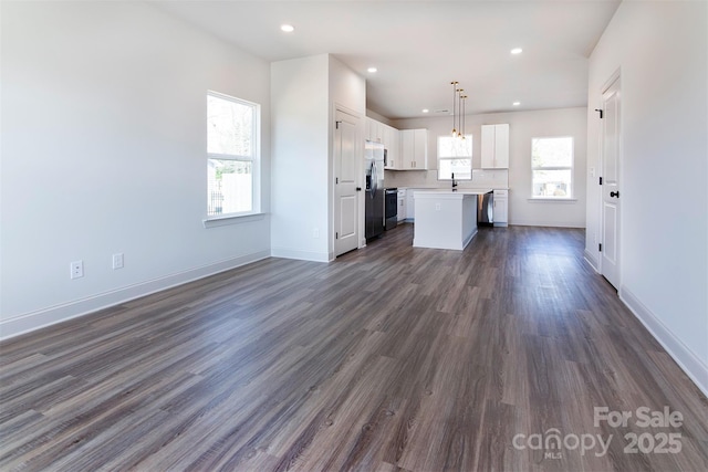 unfurnished living room with recessed lighting, dark wood-style flooring, a sink, and baseboards