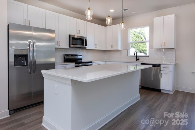 kitchen featuring white cabinets, a kitchen island, stainless steel appliances, and dark wood-type flooring