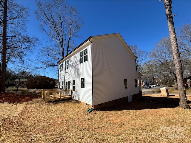 view of side of home featuring crawl space and a wooden deck