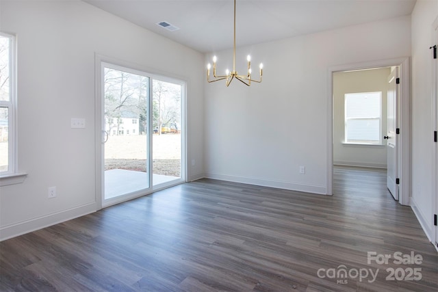 spare room featuring baseboards, dark wood finished floors, visible vents, and an inviting chandelier