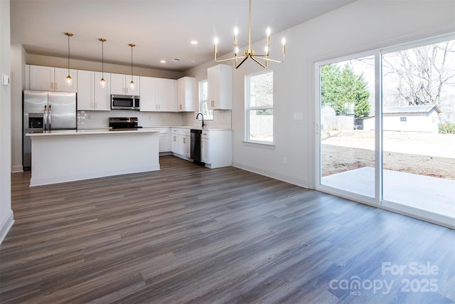 kitchen with dark wood-style floors, tasteful backsplash, light countertops, appliances with stainless steel finishes, and white cabinetry