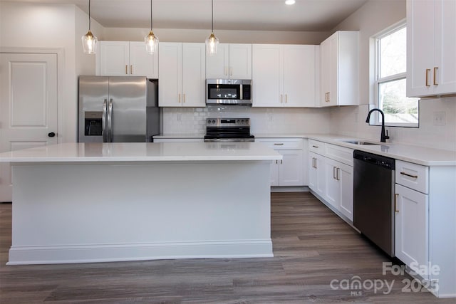 kitchen featuring a center island, stainless steel appliances, decorative backsplash, white cabinets, and a sink