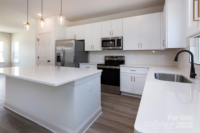 kitchen featuring stainless steel appliances, backsplash, a sink, and a center island