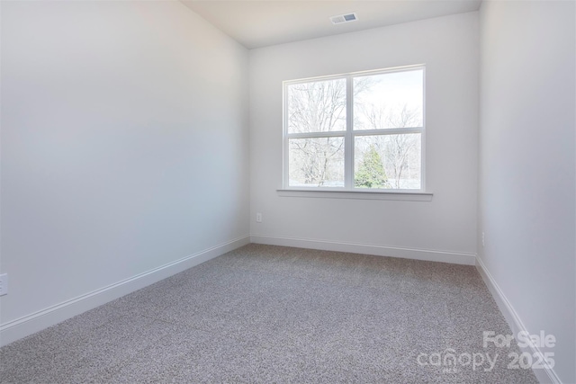 unfurnished room with carpet floors, visible vents, and baseboards