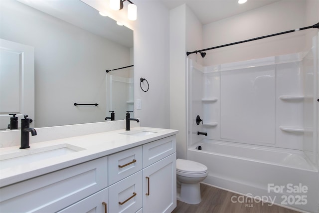 full bath featuring double vanity, wood finished floors, a sink, and toilet