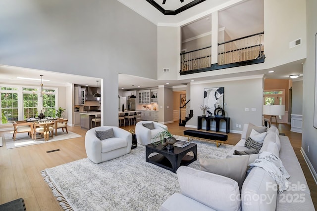 living room with visible vents, stairway, ornamental molding, wood finished floors, and baseboards