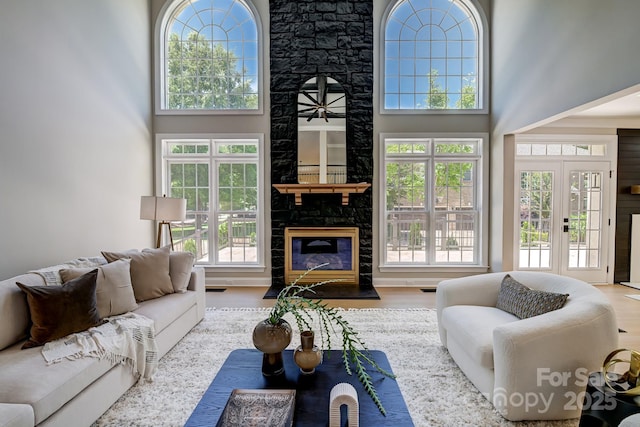 living area featuring a tile fireplace, a high ceiling, and wood finished floors