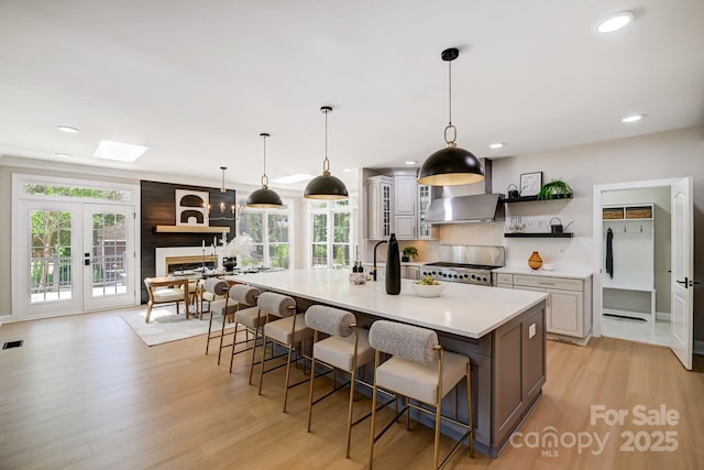 kitchen with a spacious island, stove, light countertops, a kitchen bar, and open shelves