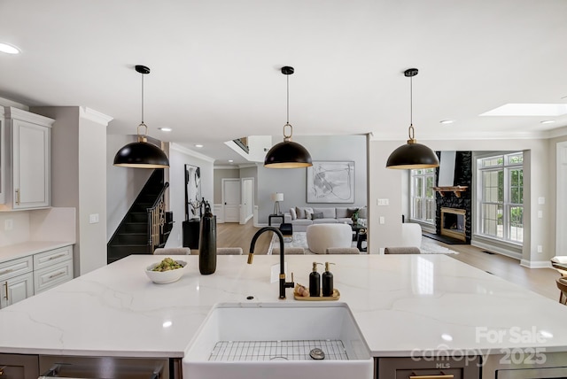 kitchen featuring an island with sink, light stone countertops, open floor plan, and a sink