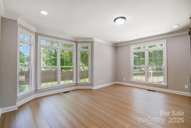 spare room with ornamental molding, light wood-style flooring, and visible vents