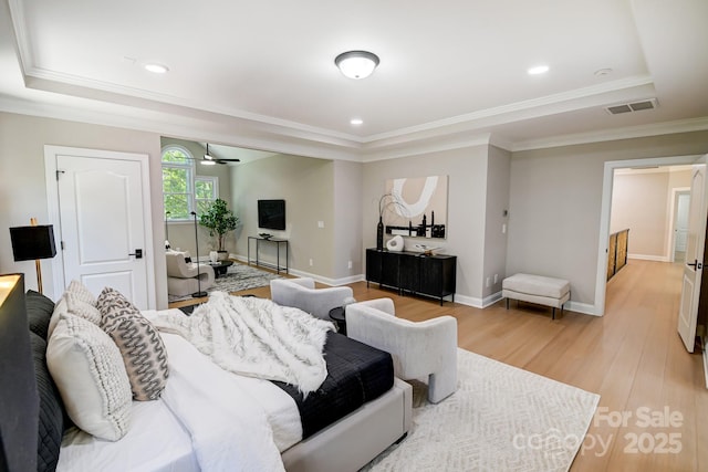 bedroom featuring light wood-type flooring, baseboards, visible vents, and a raised ceiling