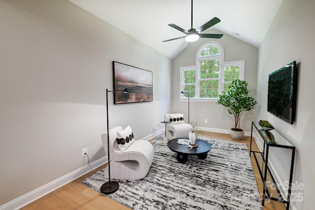 living area featuring a ceiling fan, vaulted ceiling, baseboards, and wood finished floors