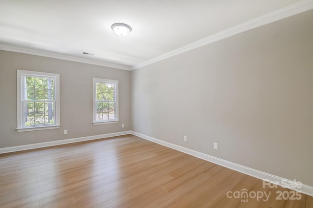 empty room featuring ornamental molding, light wood finished floors, visible vents, and baseboards