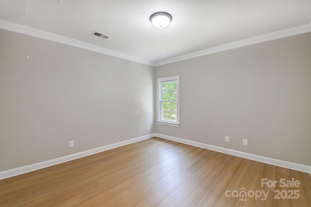 spare room with baseboards, wood finished floors, visible vents, and attic access