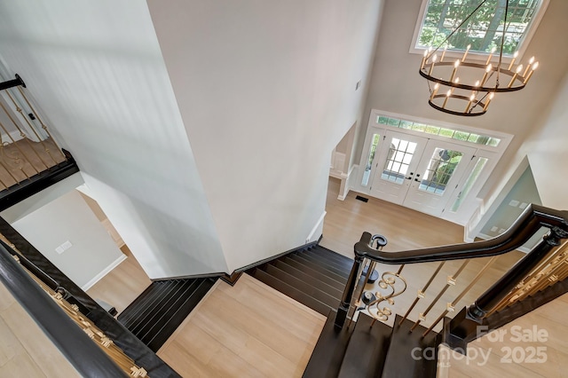 staircase featuring a wealth of natural light, french doors, a high ceiling, and wood finished floors