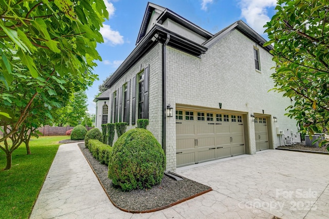 view of side of property with a garage, driveway, and brick siding