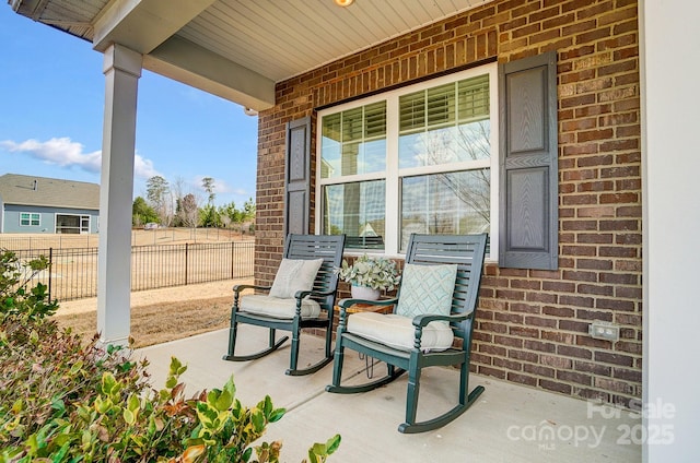 view of patio featuring a porch and fence