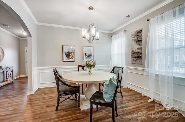 dining space with visible vents, arched walkways, crown molding, and wood finished floors