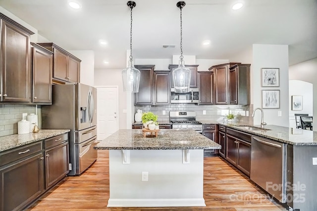 kitchen featuring stainless steel appliances, stone countertops, a sink, and visible vents