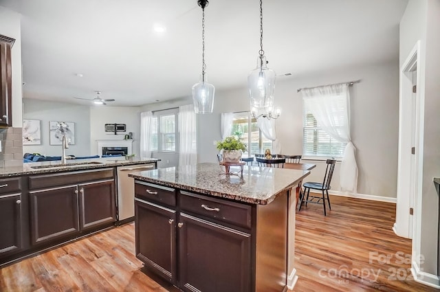 kitchen with a sink, light wood-type flooring, light stone counters, and dishwasher