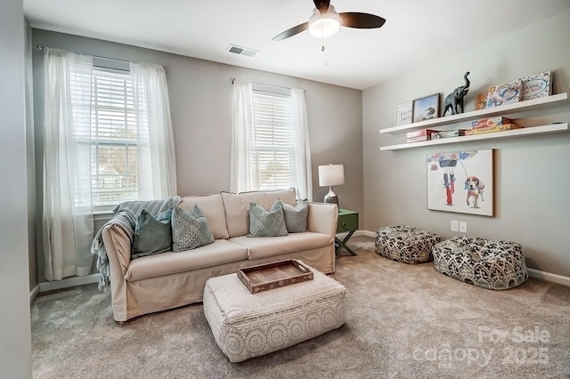 carpeted living area with a ceiling fan, visible vents, and baseboards