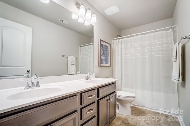 bathroom with toilet, double vanity, a sink, and visible vents