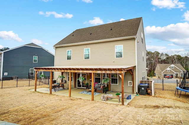 rear view of property featuring a trampoline, a patio area, and a fenced backyard