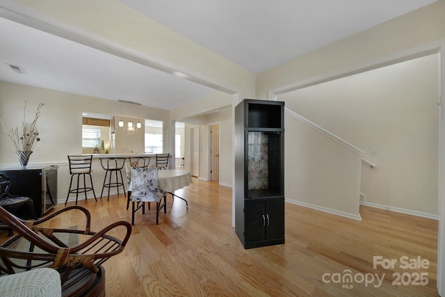 sitting room with baseboards, visible vents, and light wood-style floors